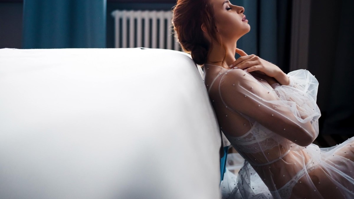 Femme en lingerie satin douce regardant par la fenêtre, atmosphère intime et rassurante