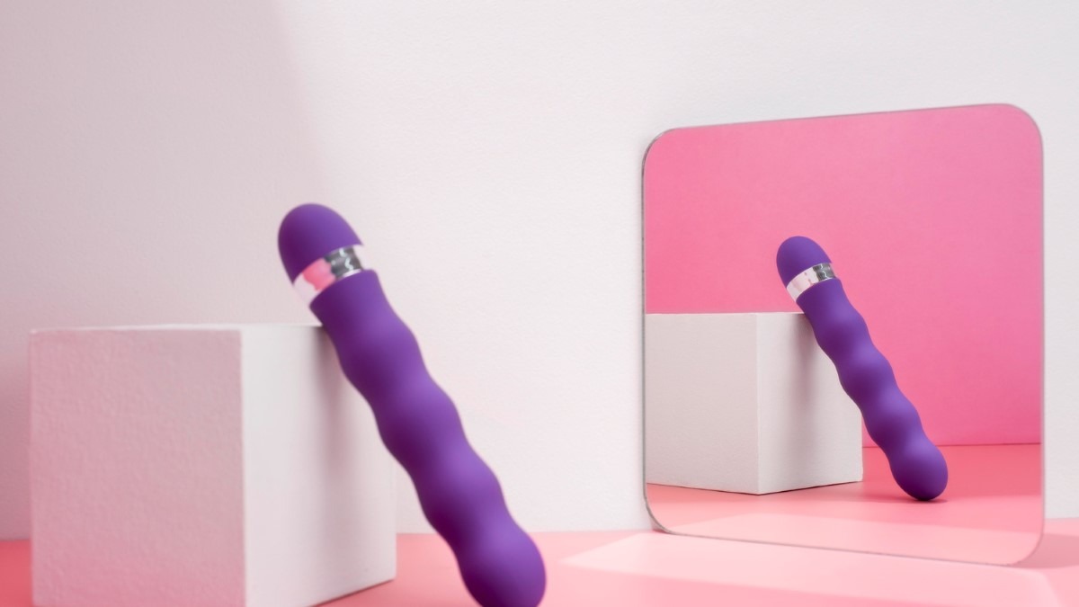 Boîte discrète et vibromasseur en silicone posé sur une serviette, ambiance douce et rassurante.