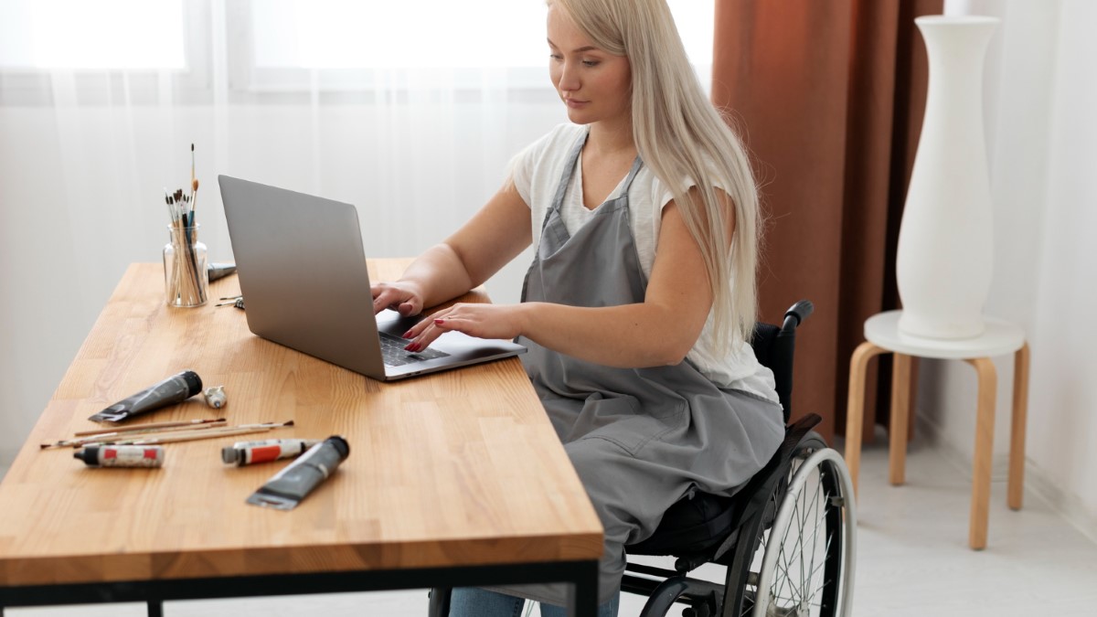 Personne en fauteuil roulant utilisant un ordinateur, symbolisant l’accès à l’information fiable et à l’accessibilité des produits.